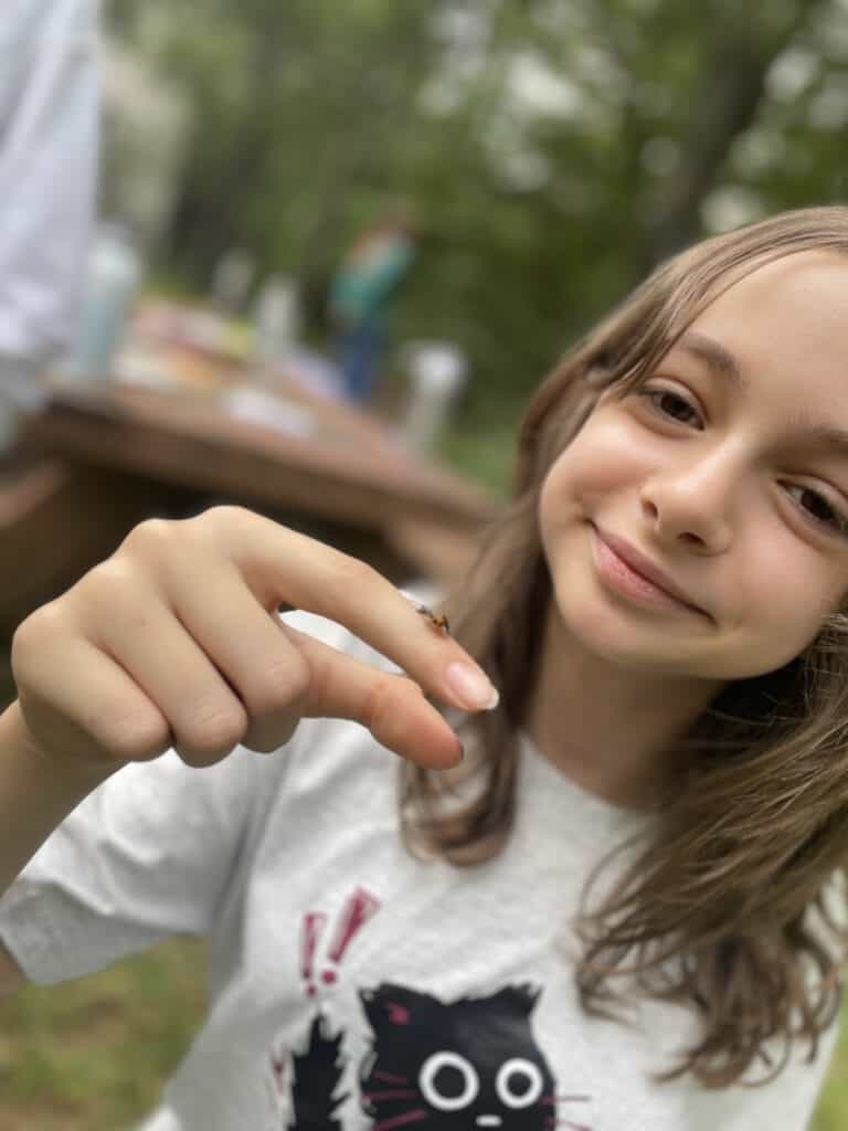 smiling girl outdoors with insect on her finger